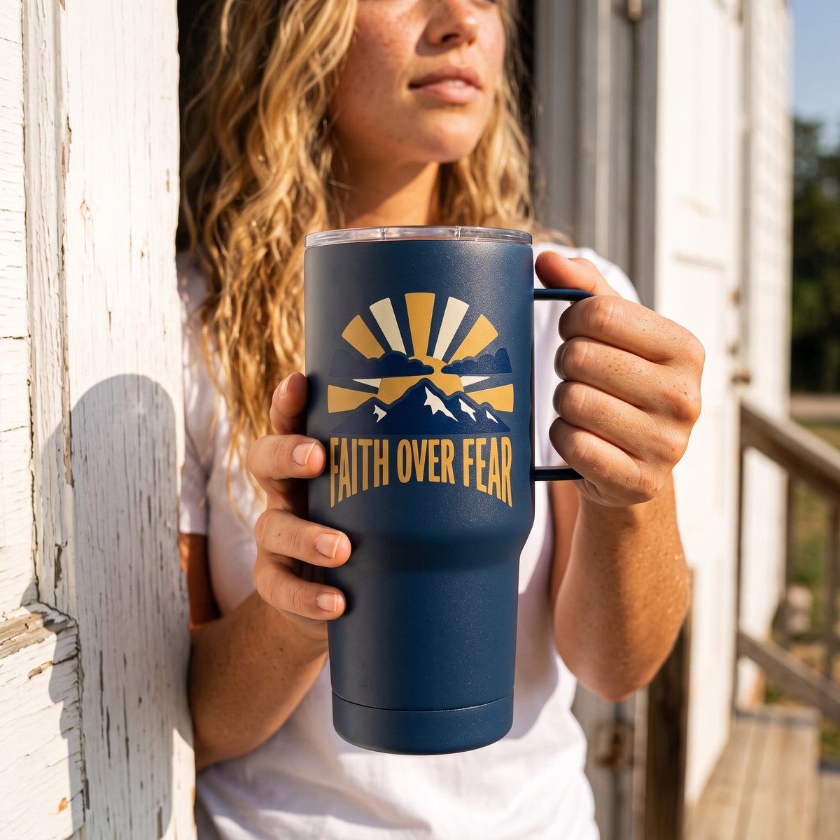 Faith Over Fear 15oz insulated mug in navy, held by an approved model, close lifestyle photograph
