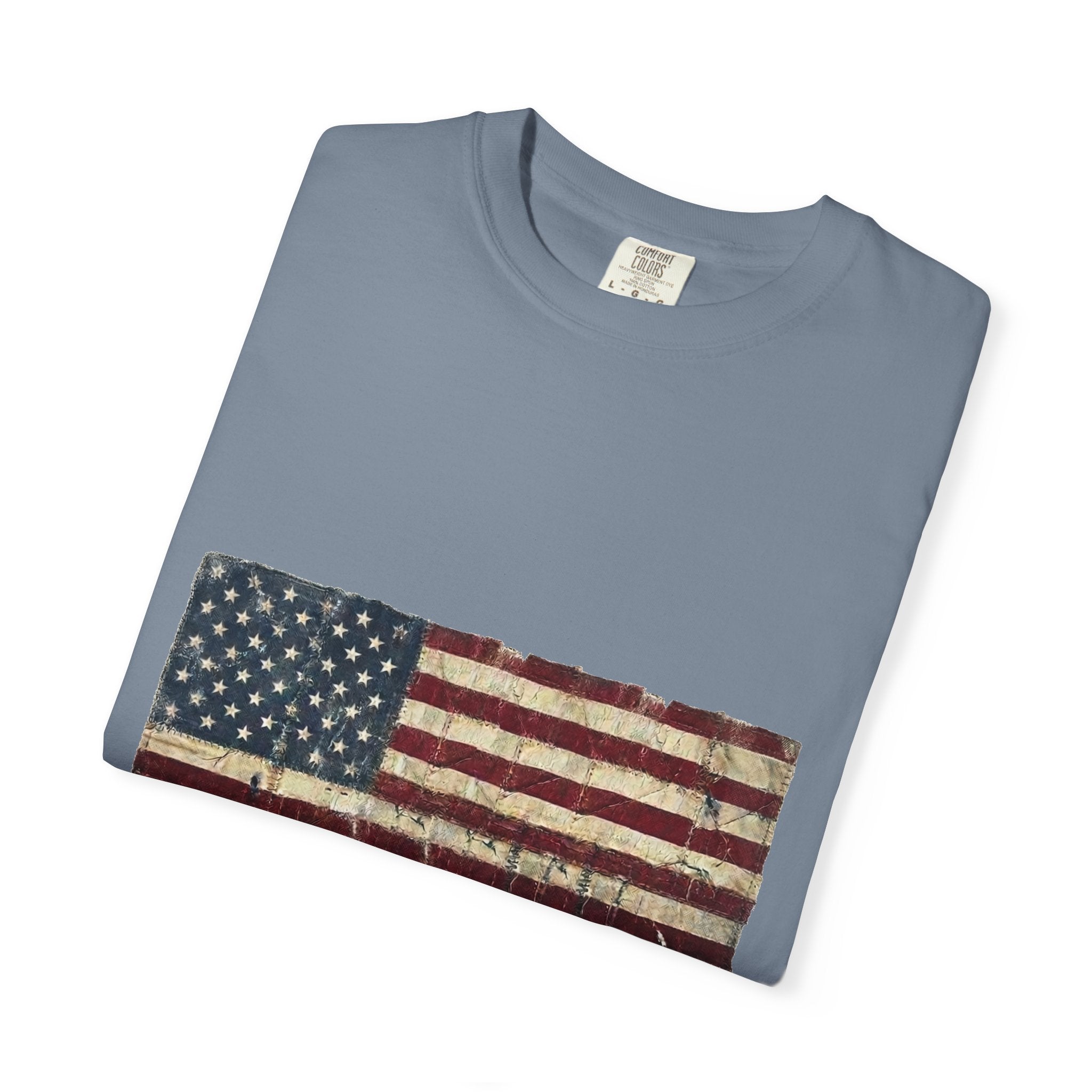 Distressed tattered US flag with HOME OF THE BRAVE lettering on a garment-dyed Comfort Colors vintage tee