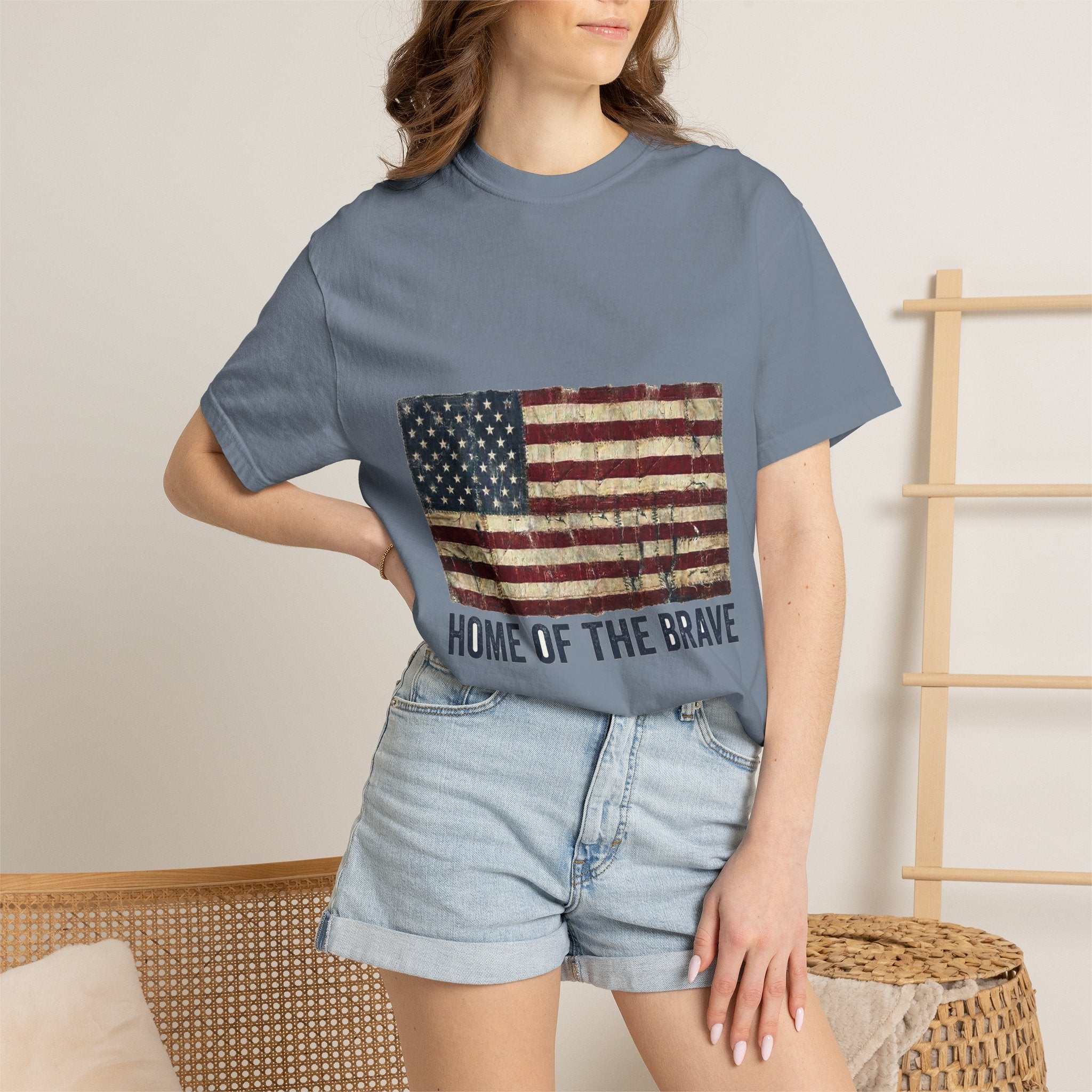 Distressed tattered US flag with HOME OF THE BRAVE lettering on a garment-dyed Comfort Colors vintage tee