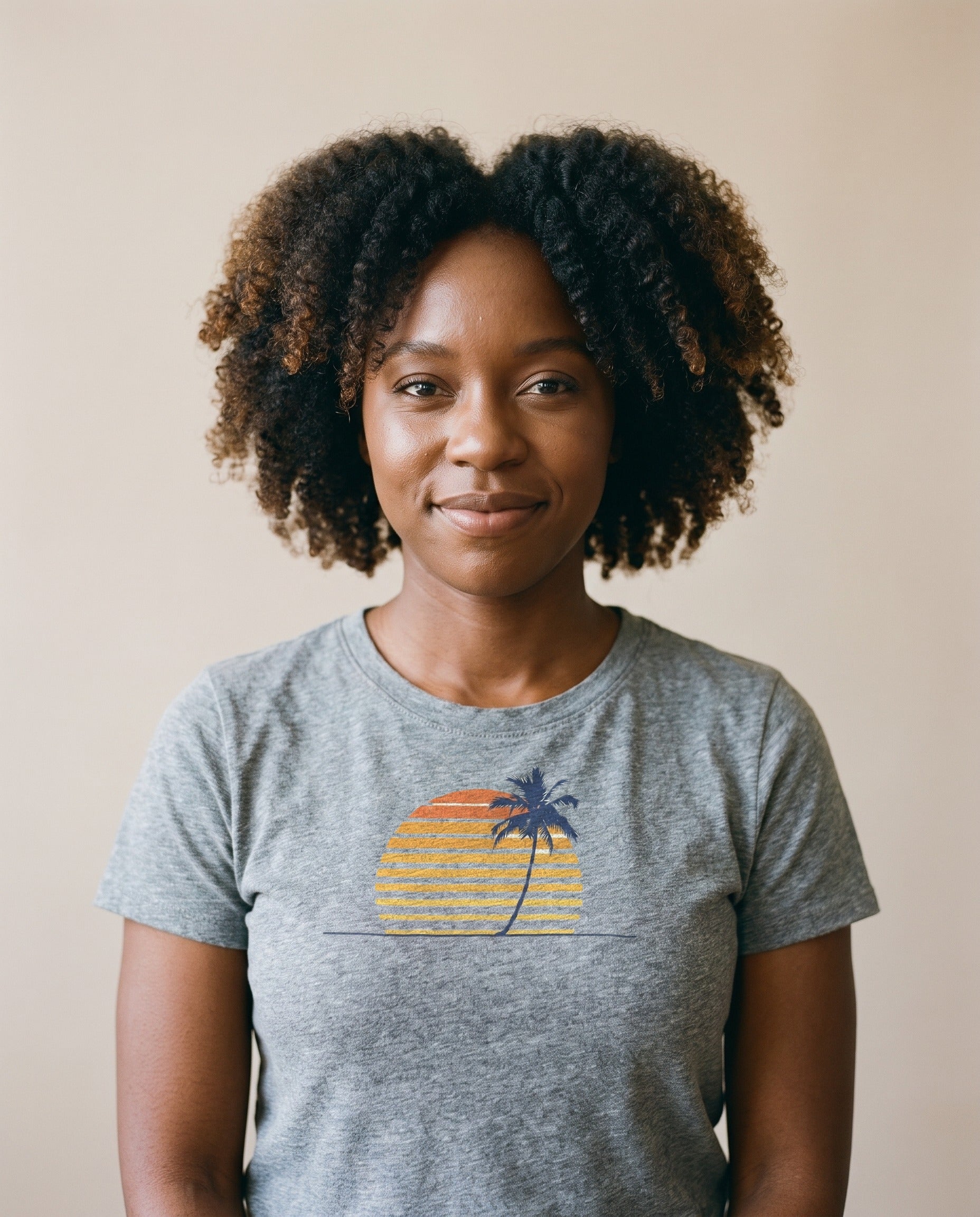 Woman wearing the Retro Palm and Sunset minimalist tee in Sport Grey, single palm silhouette over striped sunset