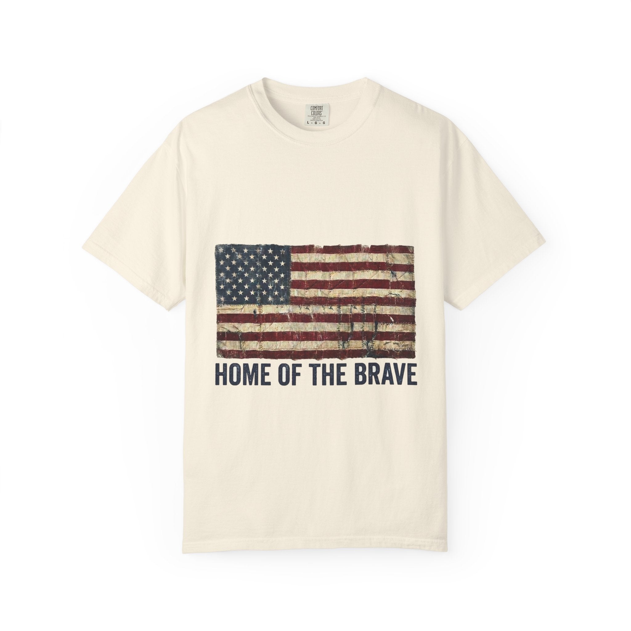 Ivory garment-dyed Comfort Colors tee with a distressed tattered US flag and HOME OF THE BRAVE lettering