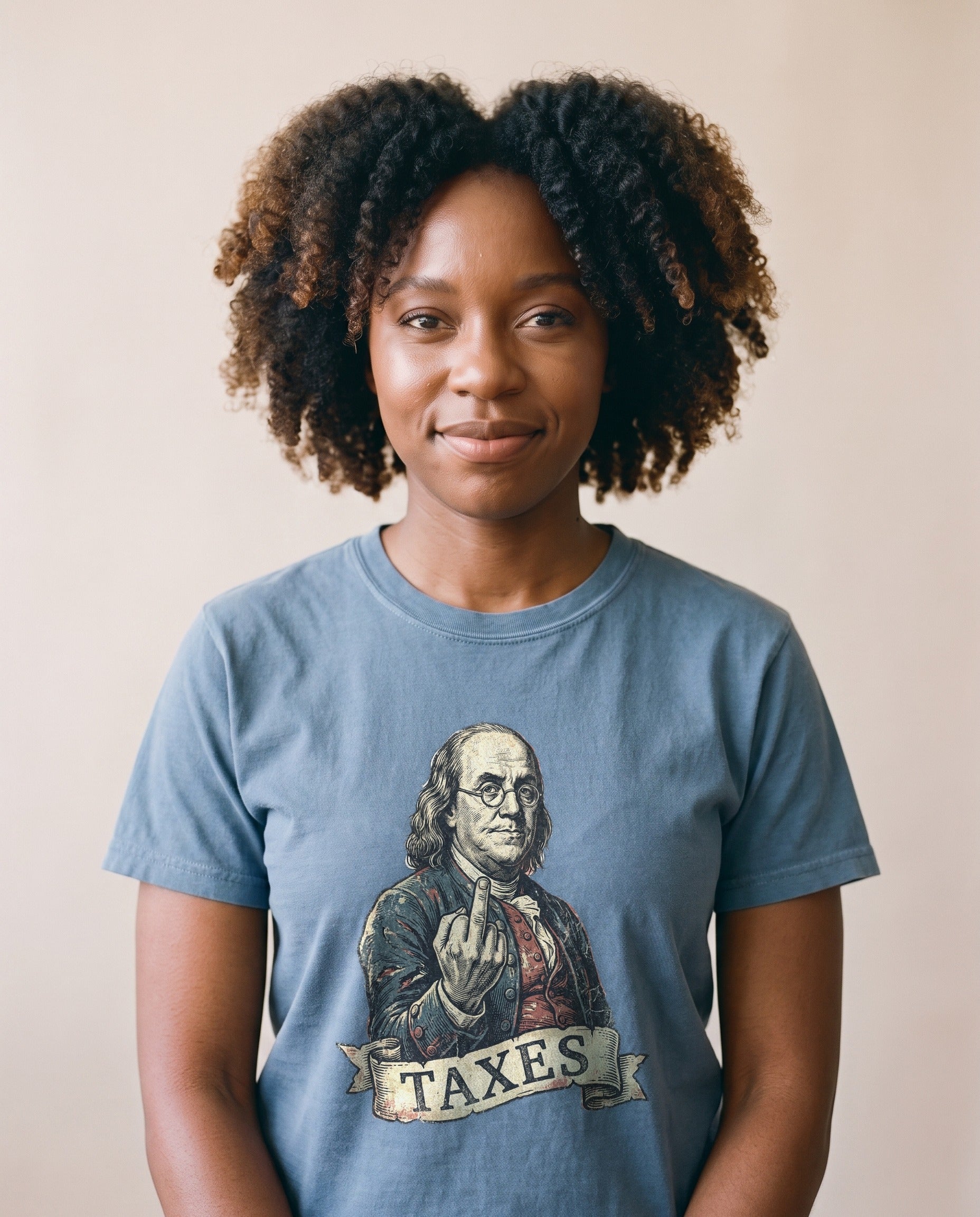 Woman wearing the Ben Franklin TAXES funny founding fathers tee in Blue Jean, vintage engraved Franklin print on garment-dyed cotton, natural light portrait