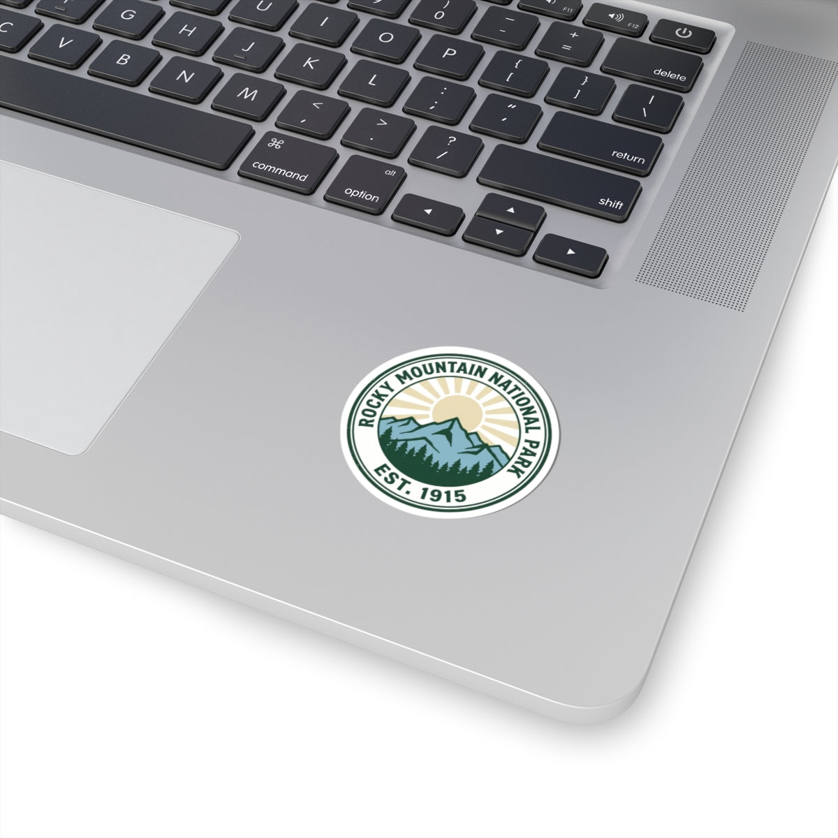 Rocky Mountain National Park sticker applied to the corner of an open silver laptop beside the keyboard