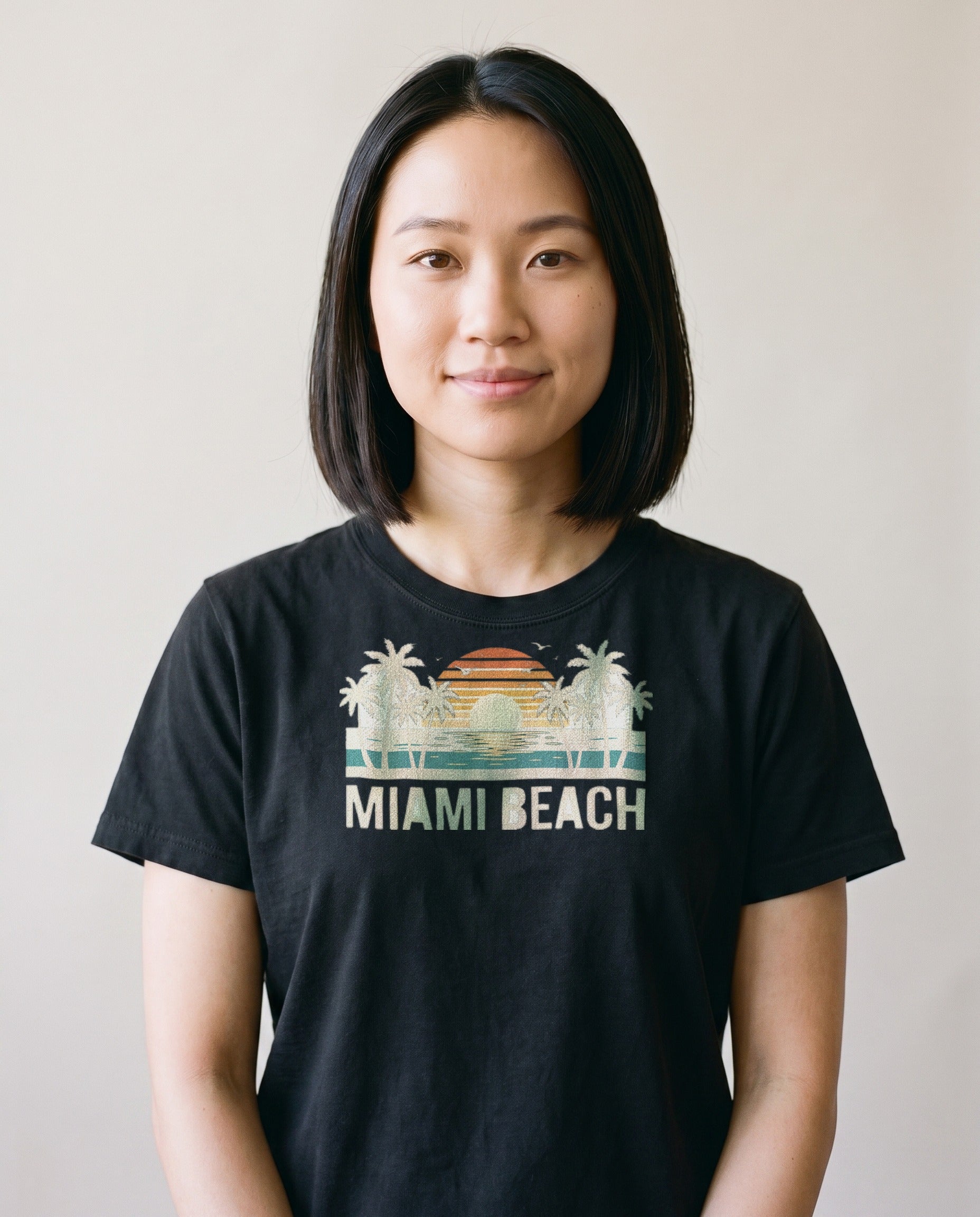 Woman wearing the Miami Beach retro tee in Black, cream palms and single striped sunset with Miami Beach lettering, corrected print