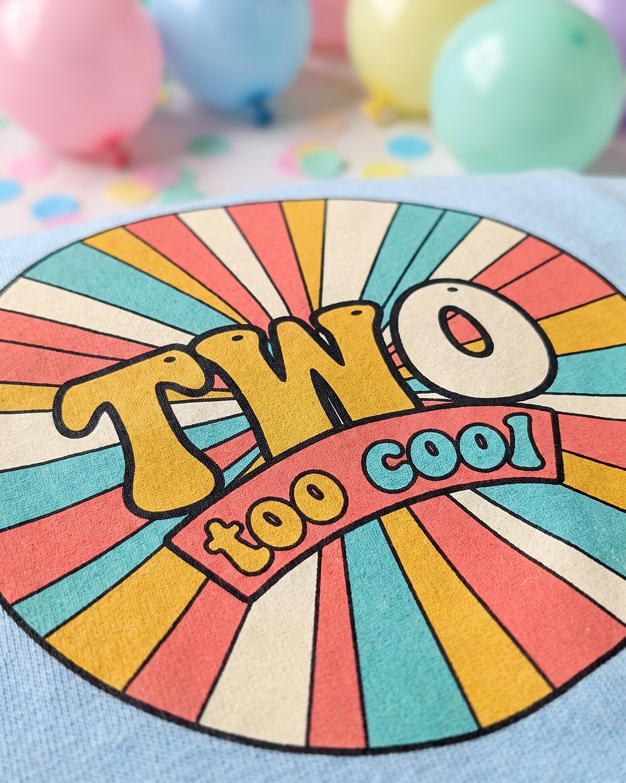 Close up of the Two Too Cool 2nd birthday retro sunburst print showing soft matte ink on cotton weave