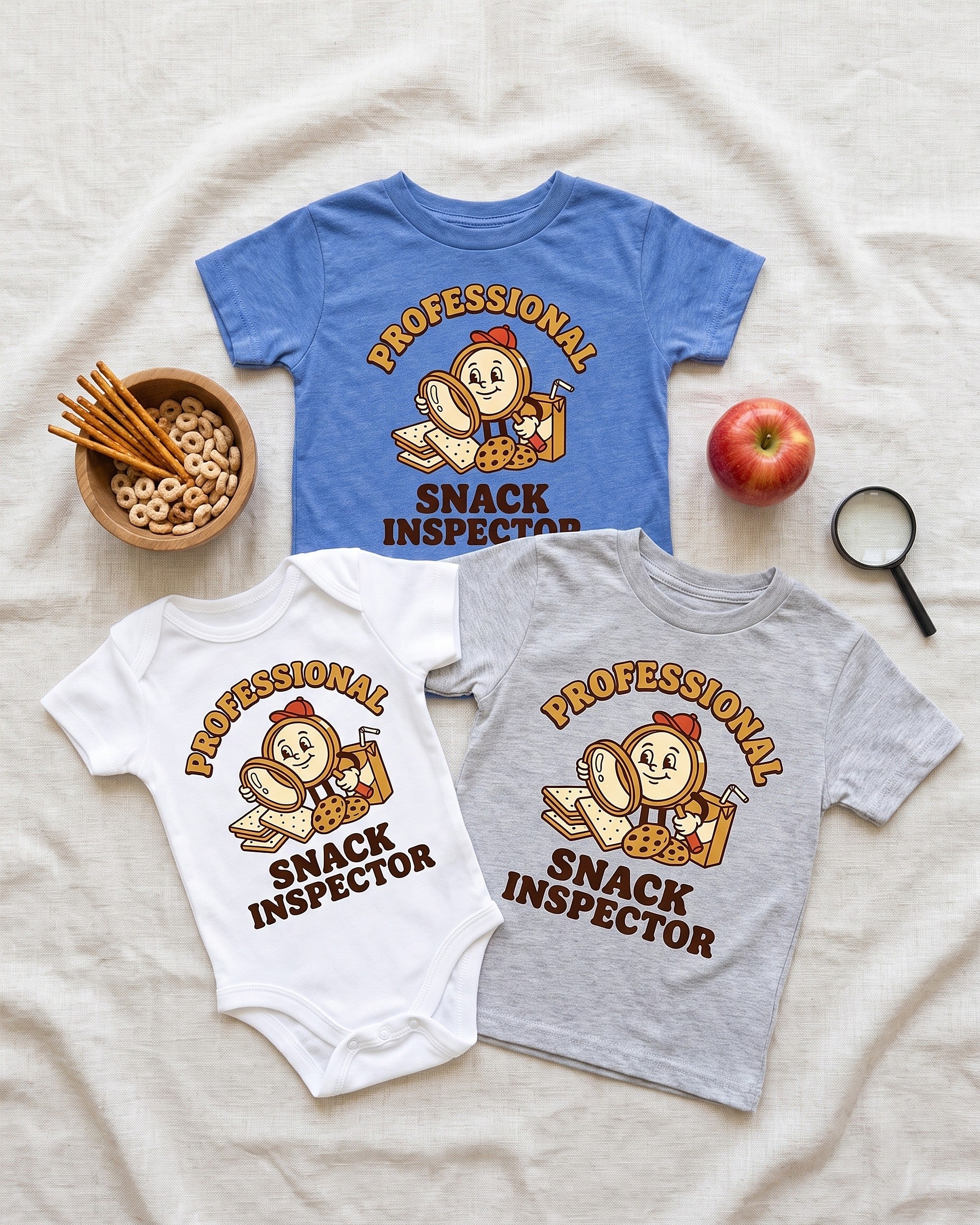 Flat lay of the Professional Snack Inspector retro mascot design across matching kids garments with playful props