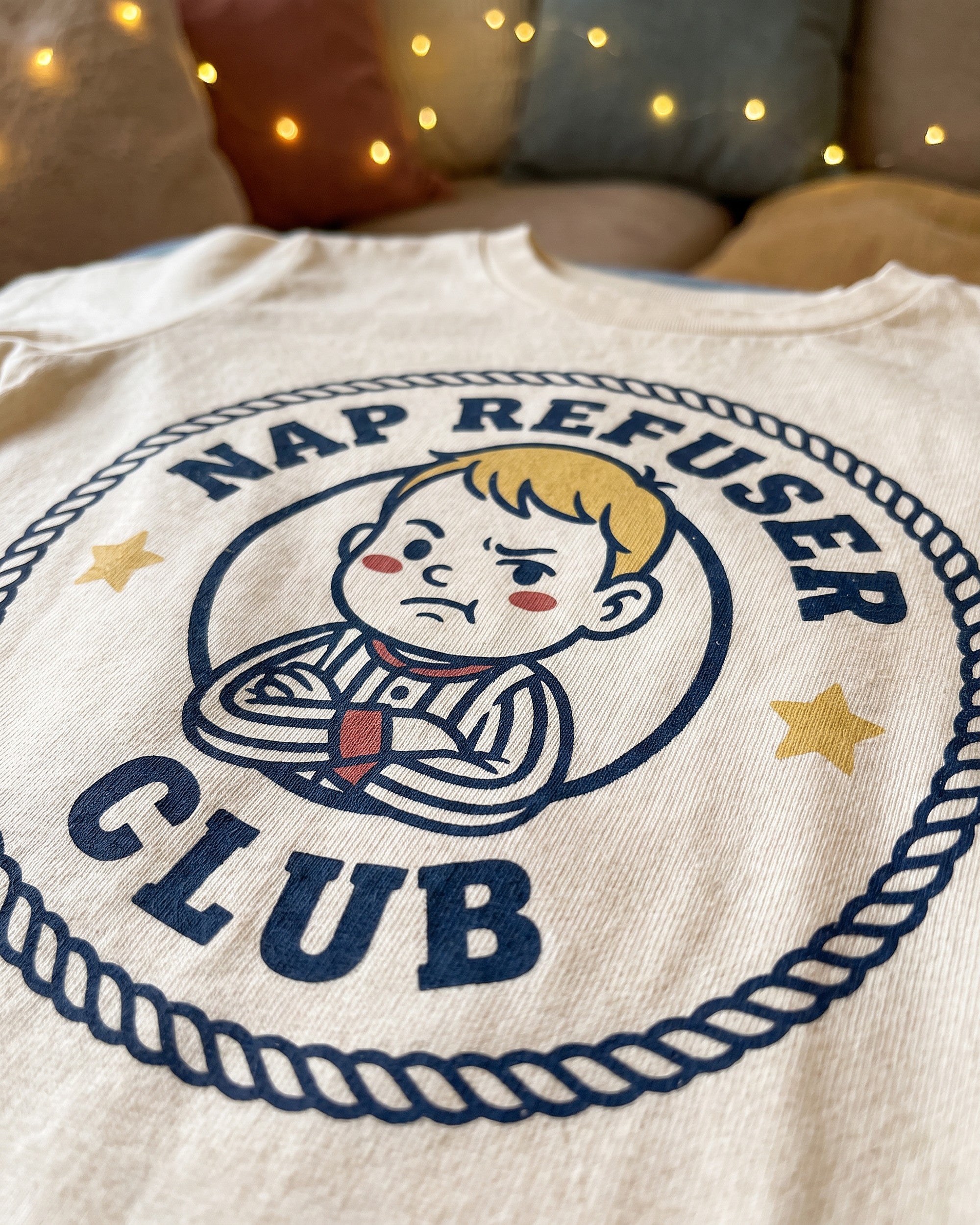 Close up of the Nap Refuser Club badge print showing soft matte ink on cotton weave