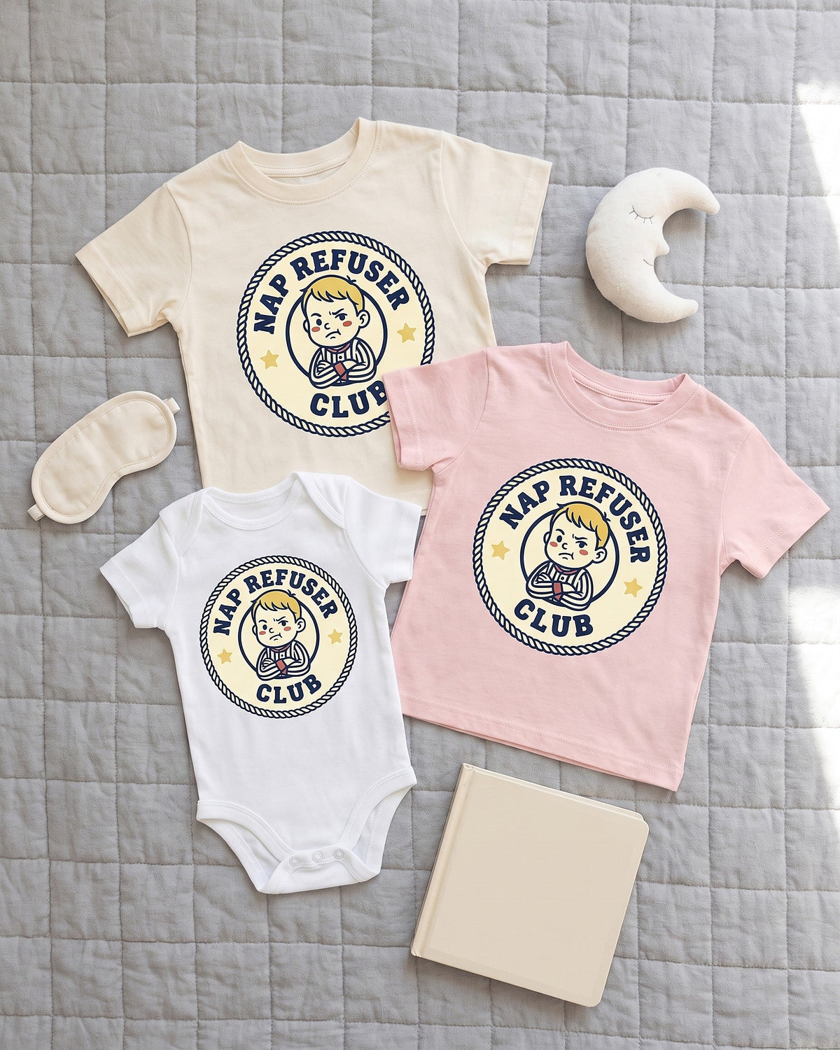 Flat lay of the Nap Refuser Club badge design across matching kids garments with playful props
