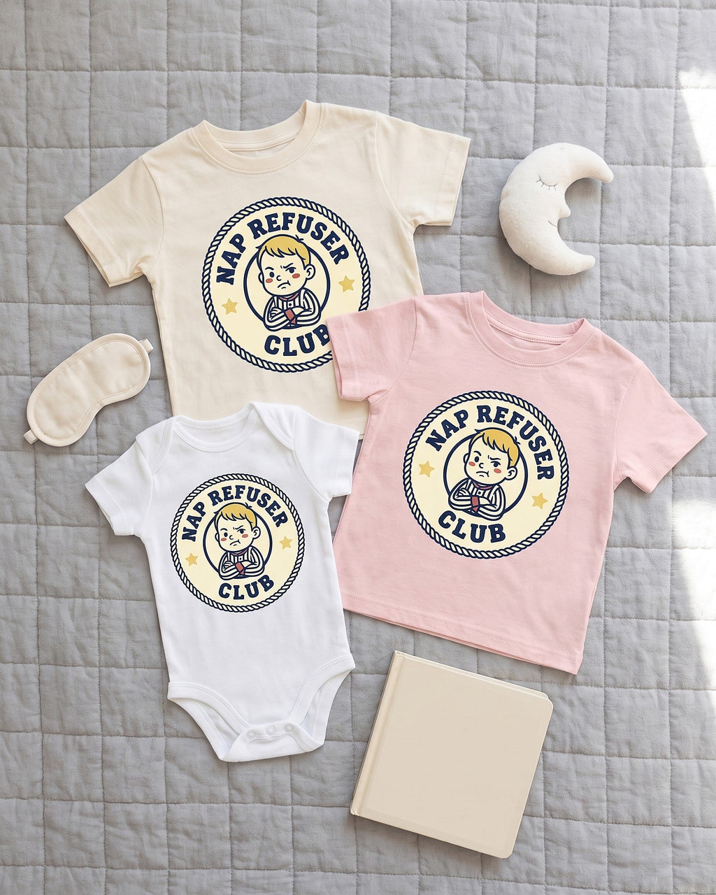 Flat lay of the Nap Refuser Club badge design across matching kids garments with playful props