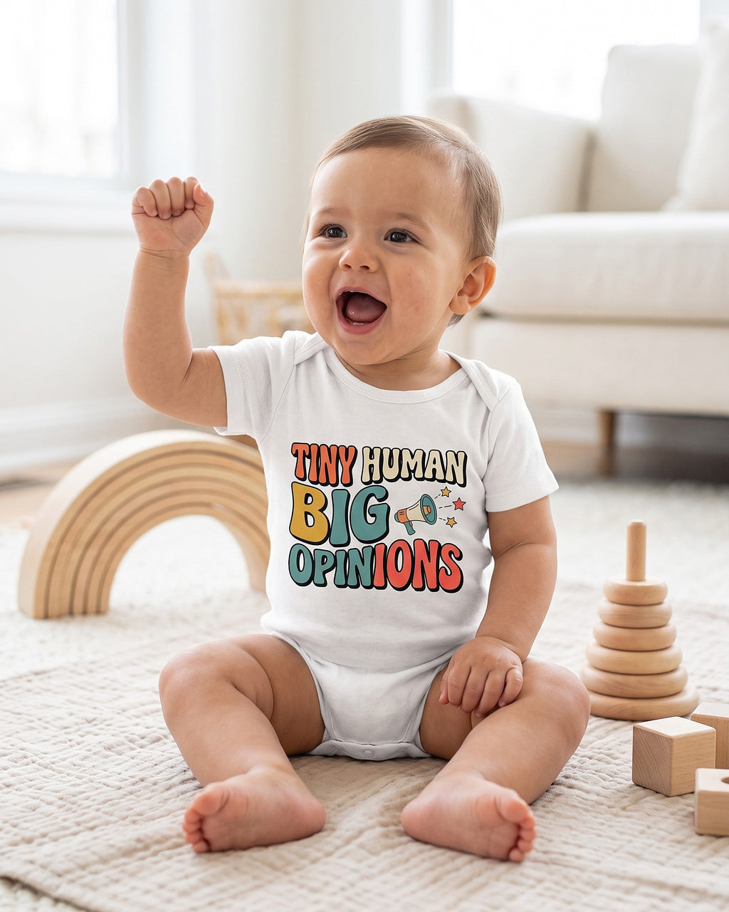 Tiny Human Big Opinions design on a white baby bodysuit worn by a happy baby