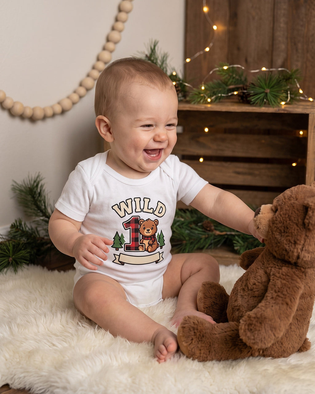 Wild One plaid bear first birthday design on a white baby bodysuit worn by a happy baby