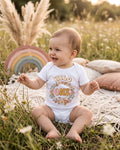 Wild One boho floral bunny first birthday design on a white baby bodysuit worn by a happy baby