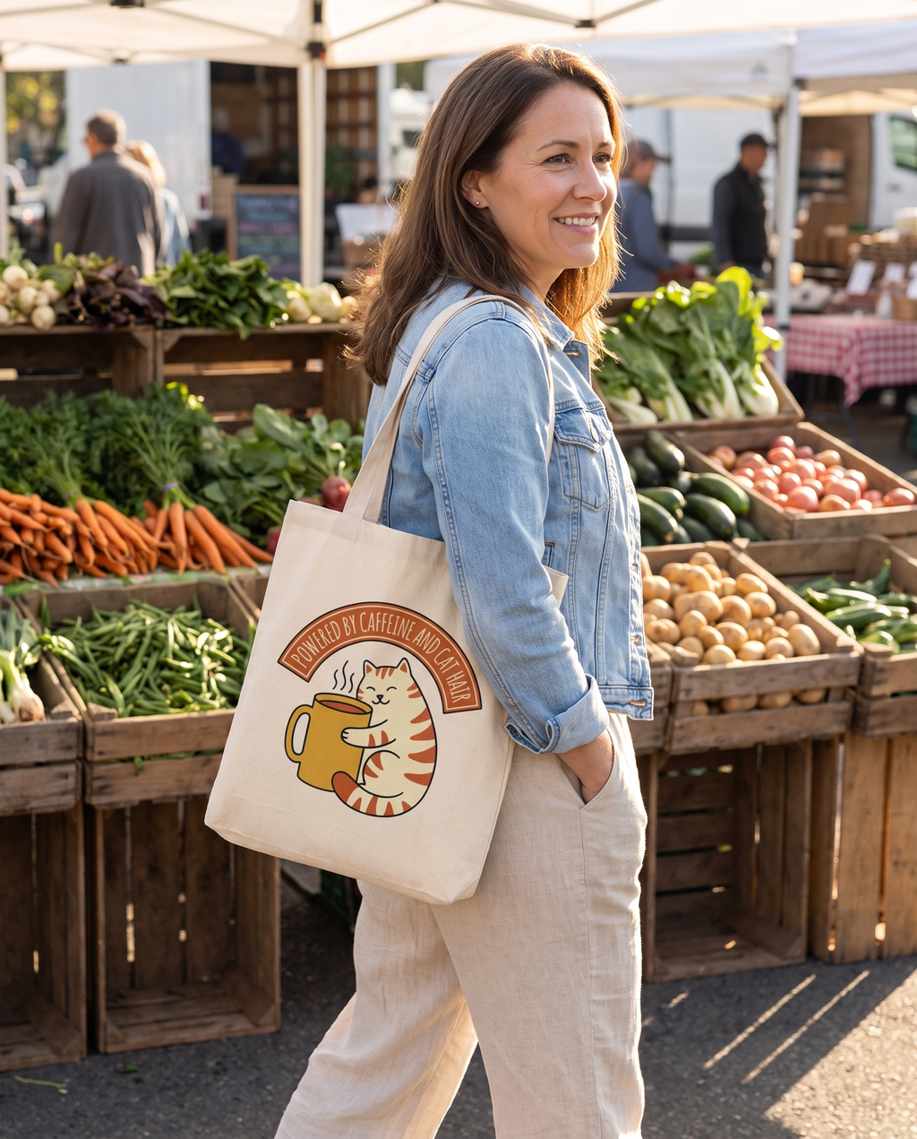 Woman carrying the Cat Coffee Powered by Caffeine and Cat Hair natural canvas tote at a farmers market, print fully legible