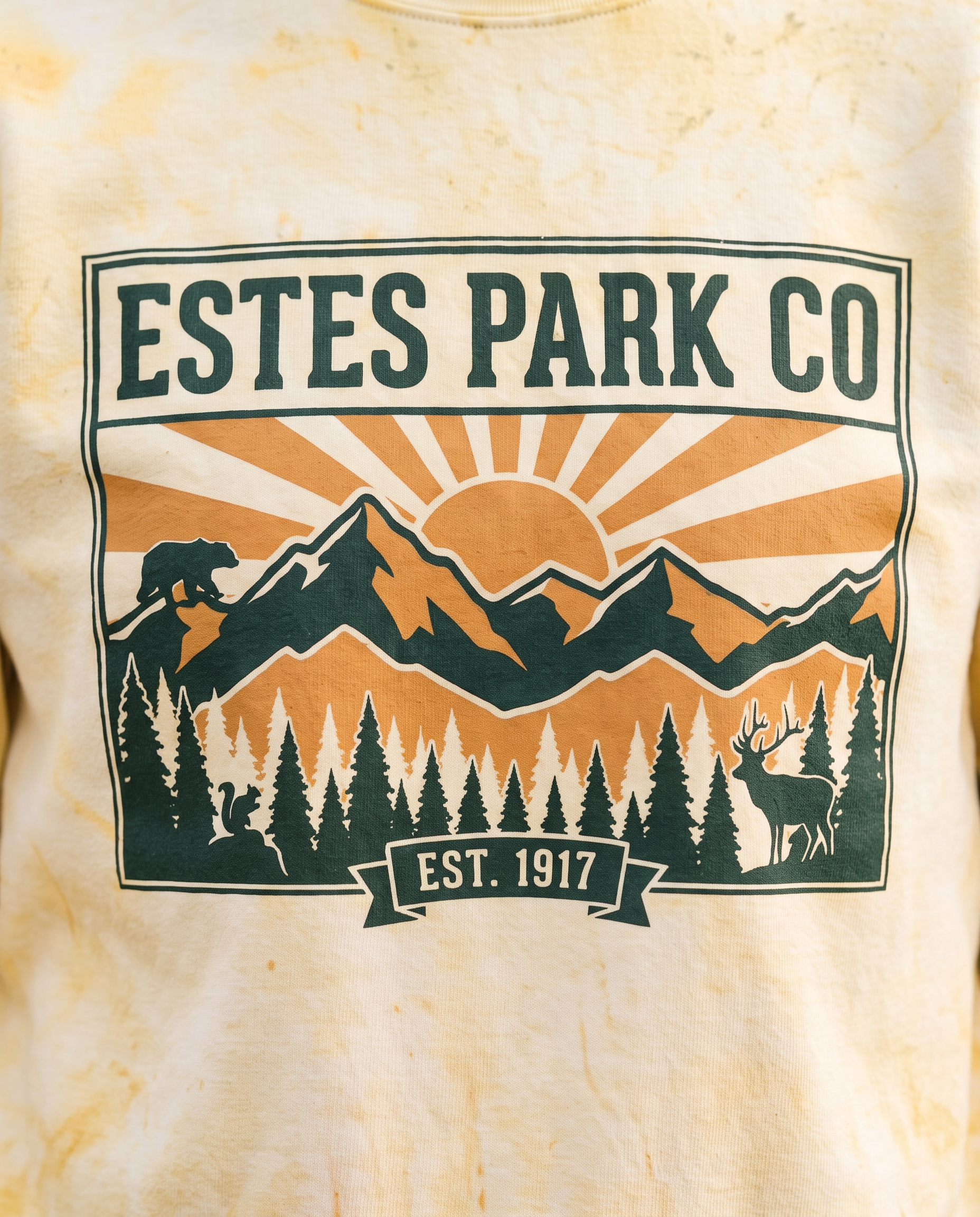 Estes Park CO hidden wildlife badge close-up on a citrine Comfort Colors crewneck sweatshirt, bear elk and squirrel design, EST. 1917