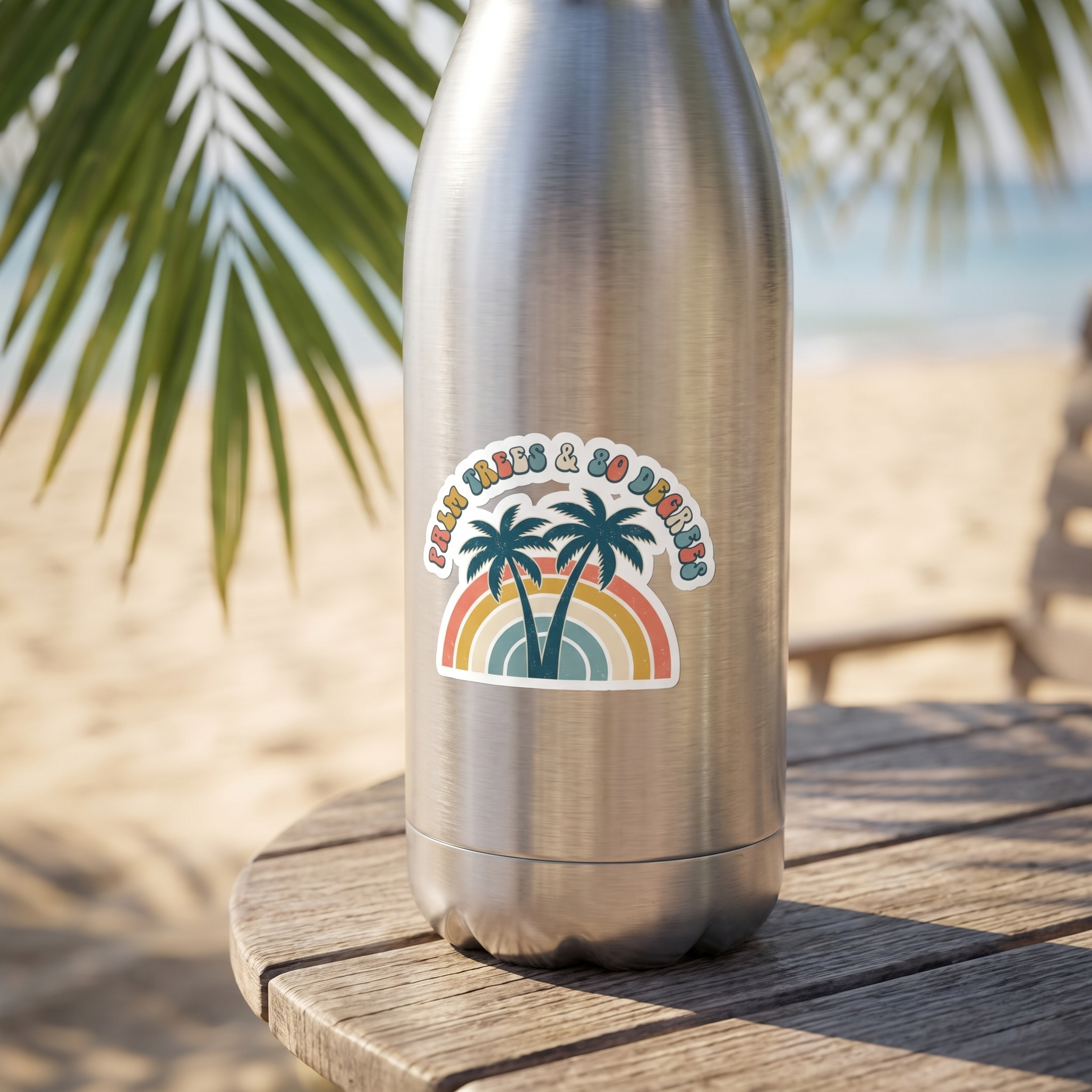 Palm Trees and 80 Degrees vinyl sticker on a stainless steel water bottle at the beach, retro rainbow palms design, die-cut sticker lifestyle photo