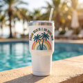 Palm Trees and 80 Degrees 32oz insulated tumbler with straw lid on a sunny poolside ledge, retro rainbow palms design, lifestyle photo