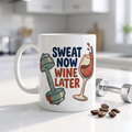 Sweat Now Wine Later 11oz mug on a bright kitchen counter with coffee beans and a dumbbell, funny gym and wine mug