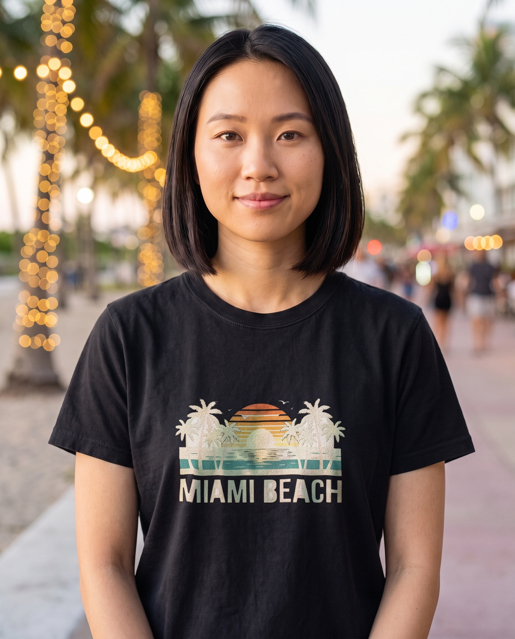 Woman on a string lit South Beach promenade in the Miami Beach retro tee in Black, cream ink and sunset design visible