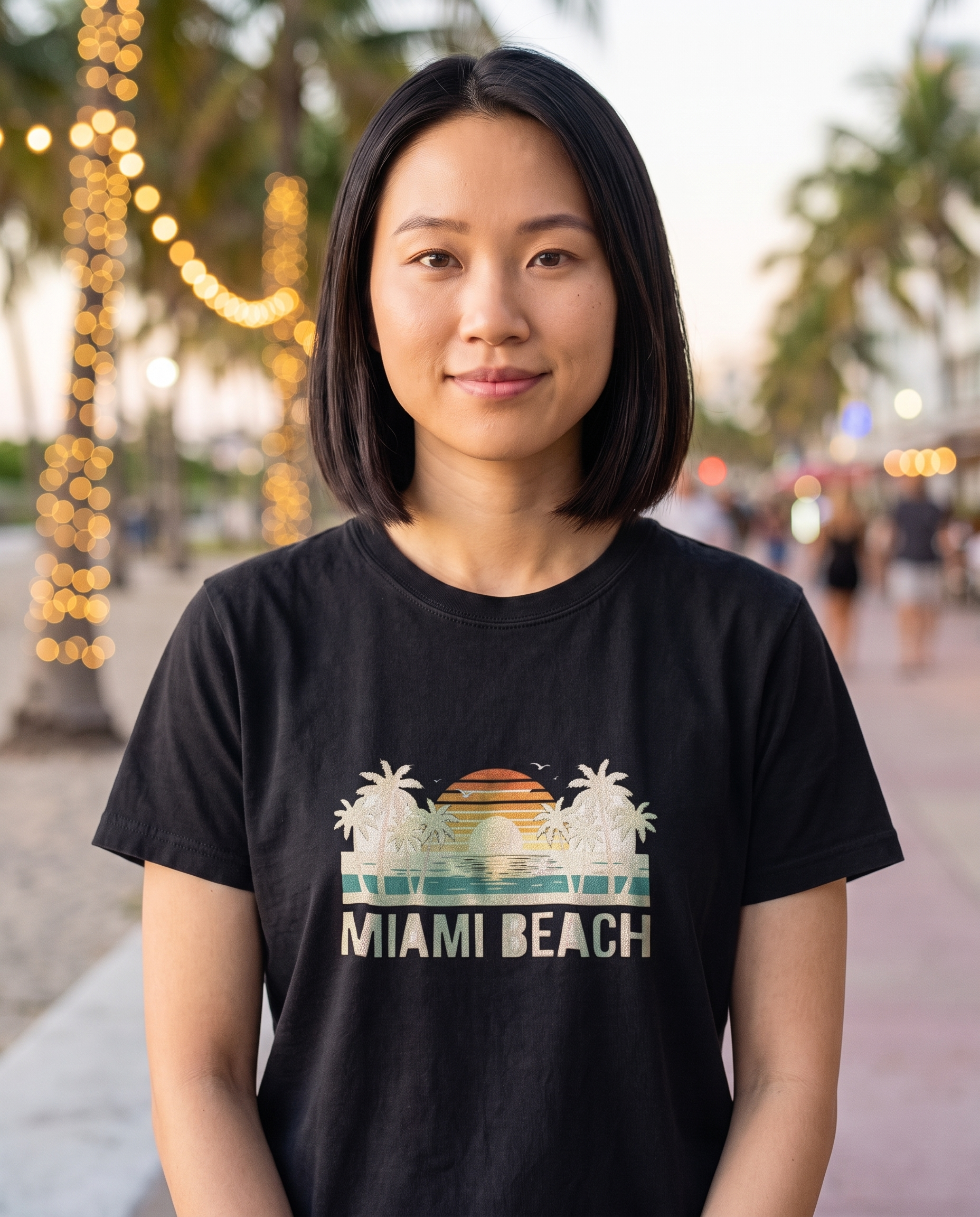 Woman on a string lit South Beach promenade in the Miami Beach retro tee in Black, cream ink and sunset design visible