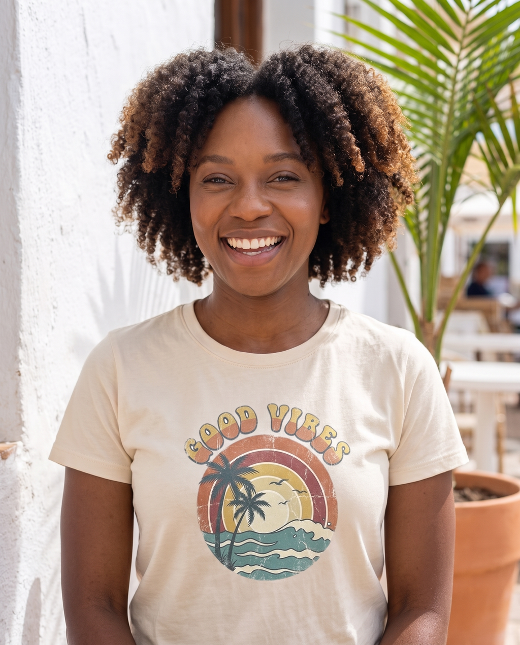Good Vibes retro beach tee in natural cream on a coastal cafe terrace
