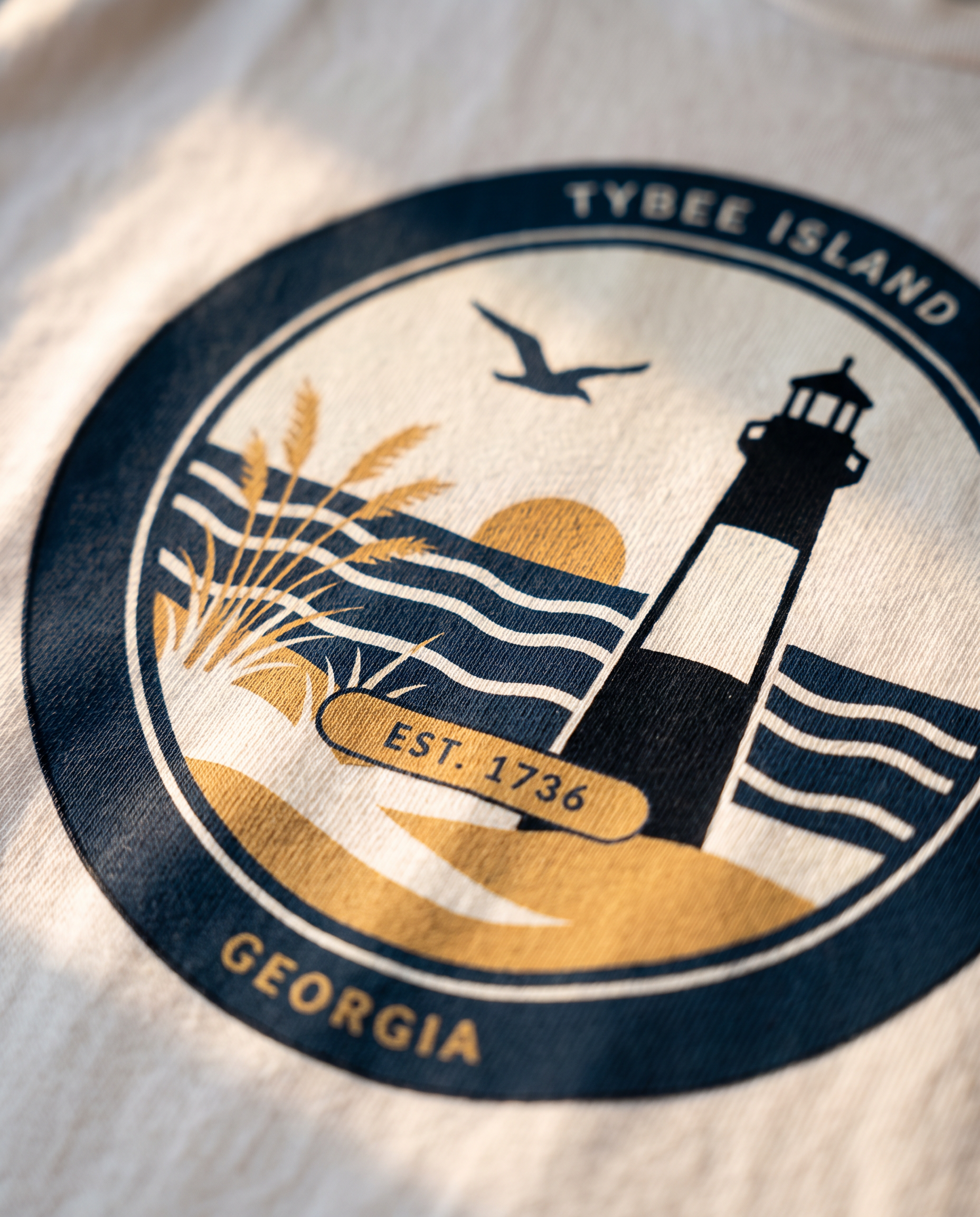 Macro detail of the Tybee Island lighthouse badge print showing matte screen print ink on cotton