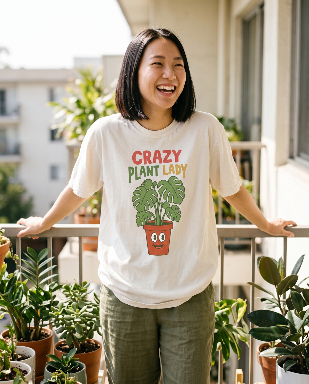 Crazy Plant Lady tee in Ivory on a plant-filled balcony, lifestyle photograph