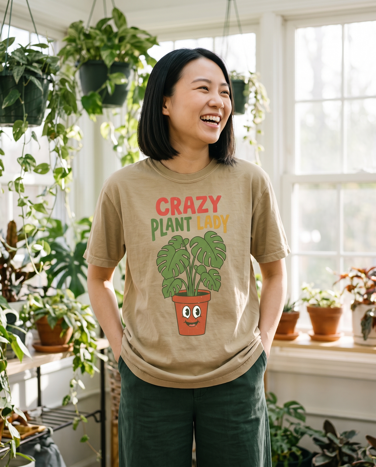 Crazy Plant Lady tee in Khaki in a sunroom full of plants, lifestyle photograph