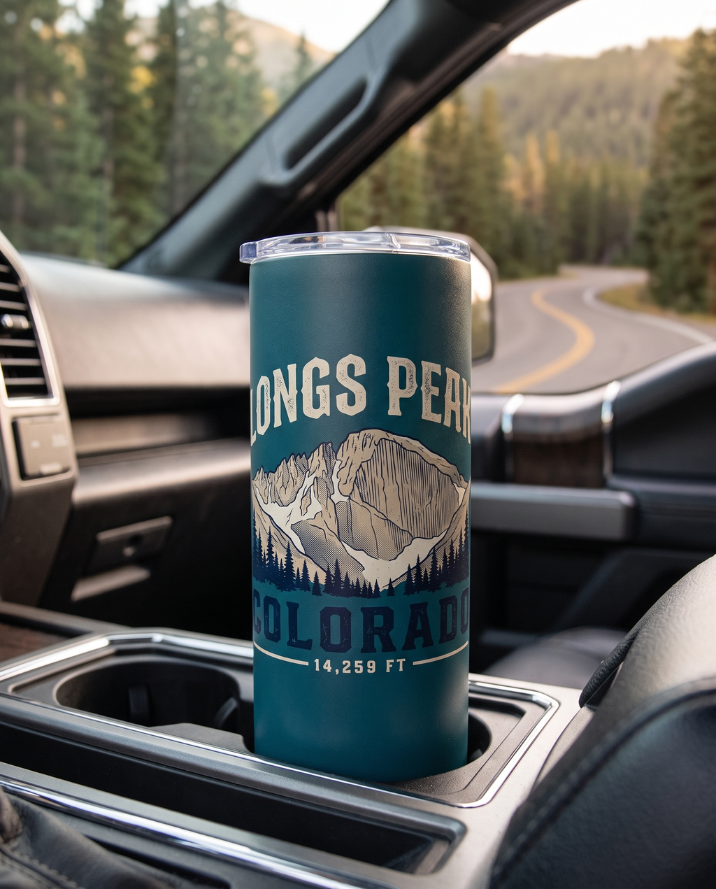 Longs Peak Colorado 20oz insulated tumbler in Teal in a truck cup holder on a mountain road