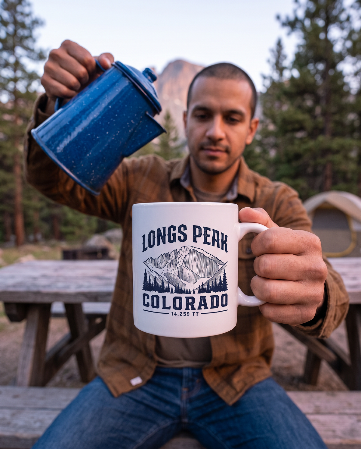Man at a campsite pouring coffee into a white Longs Peak Colorado mug, 14,259 FT, lifestyle photograph