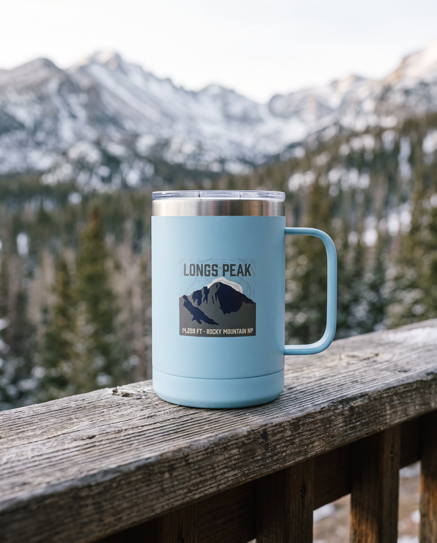 Light Blue Longs Peak 15oz insulated coffee tumbler on a cabin porch rail with Rocky Mountain peaks behind