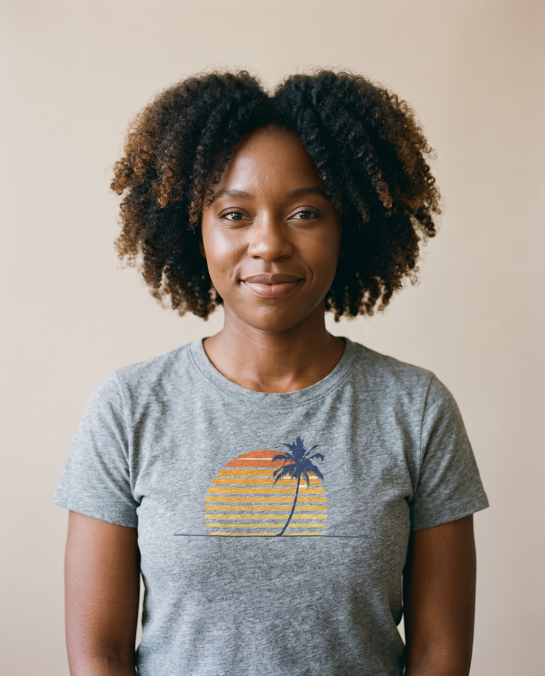 Woman wearing the Retro Palm and Sunset minimalist tee in Sport Grey, single palm over a striped sunset centered on the chest