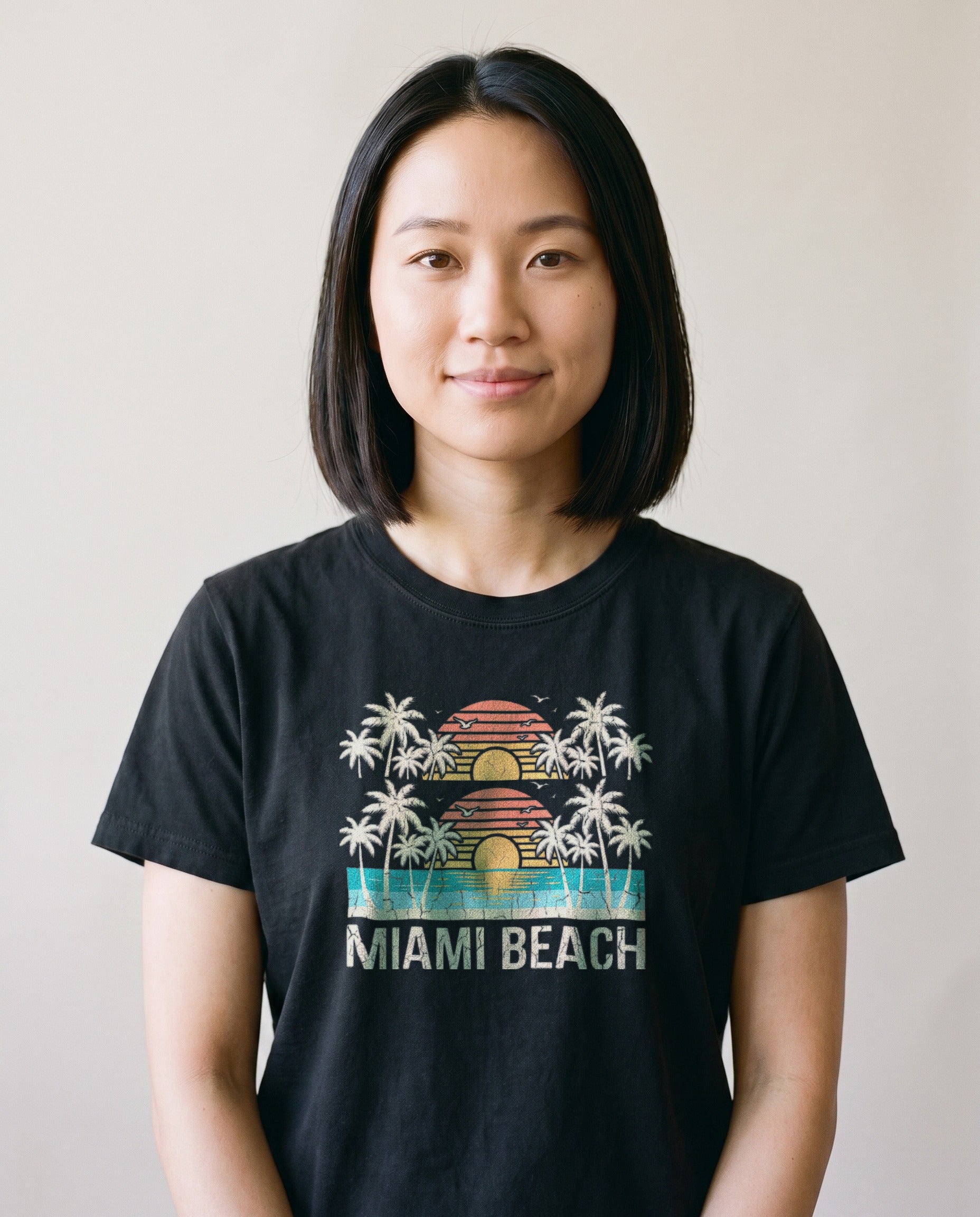 Woman wearing the Miami Beach retro tee in Black, cream ink palms and striped sunset with Miami Beach lettering