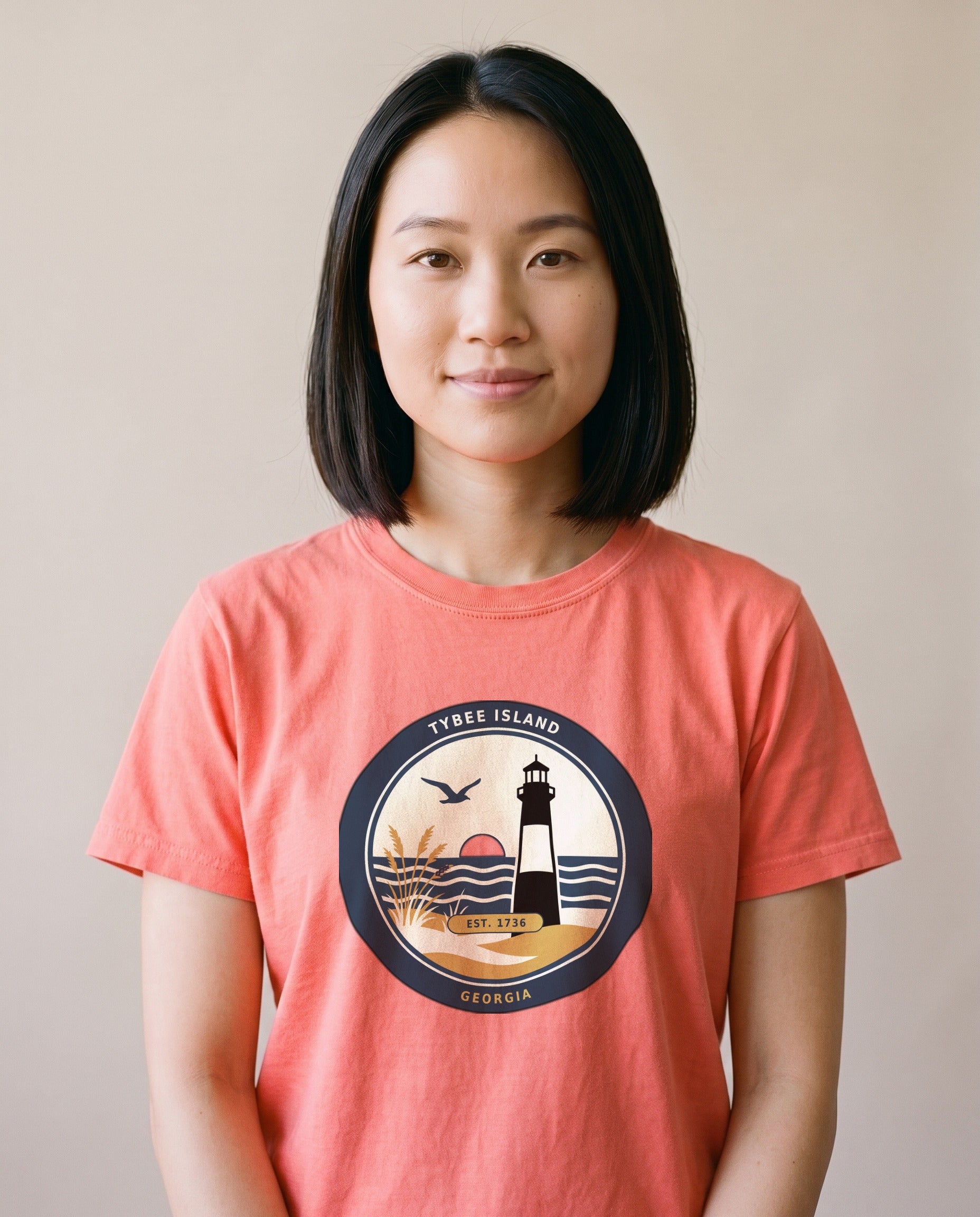 Woman wearing the Tybee Island Georgia lighthouse badge tee in Bright Salmon, vintage coastal badge print