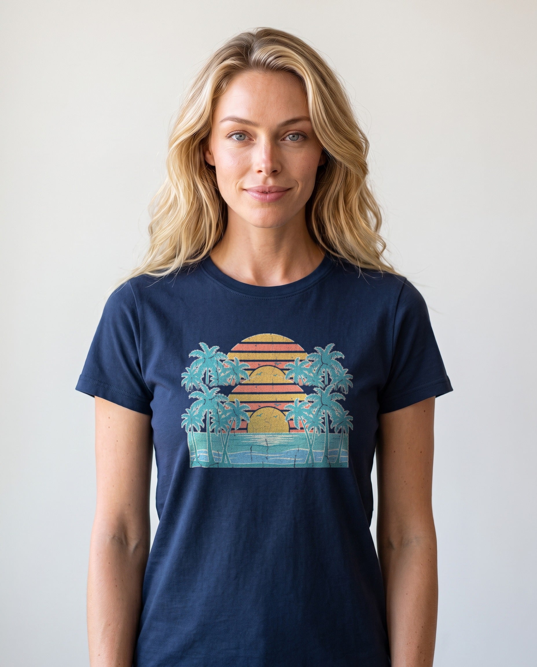 Woman wearing the Retro Beach Sunset tee in True Navy, cream ink palms and layered sunset over ocean waves